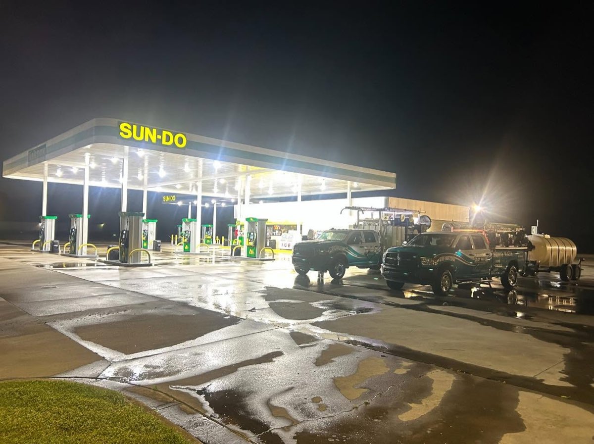 Carolina Soft Wash trucks cleaning a gas station at night
